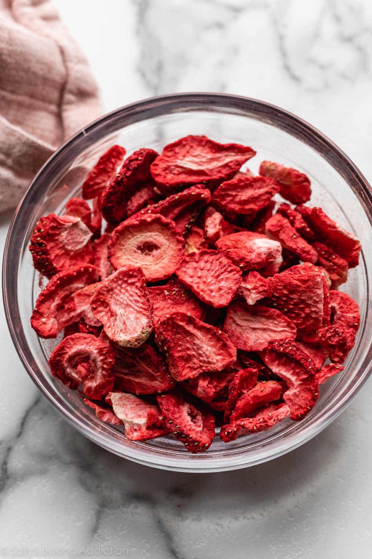 freeze-dried strawberries in glass bowl on marble counter.