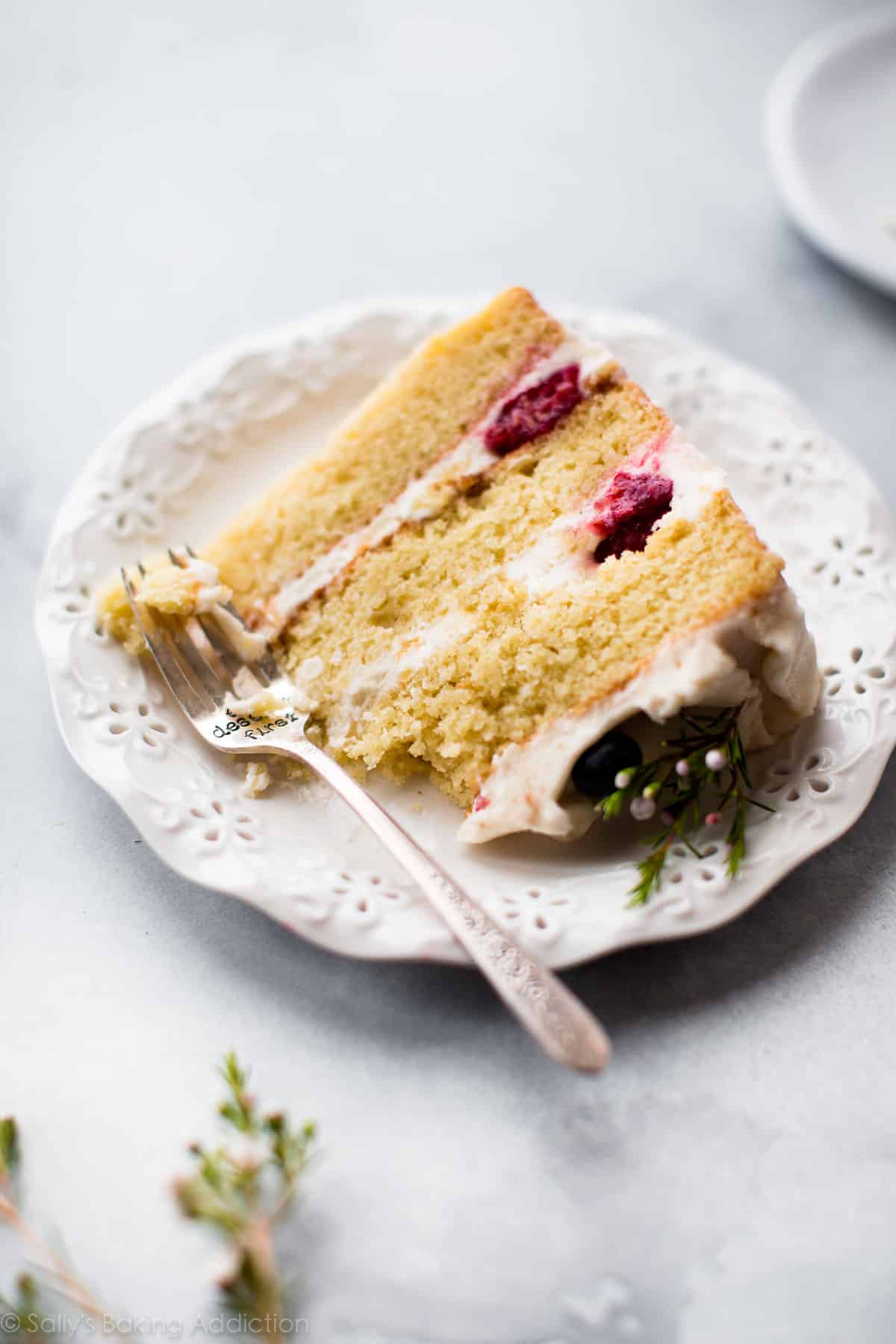 Slice of vanilla cake with raspberries on a white plate