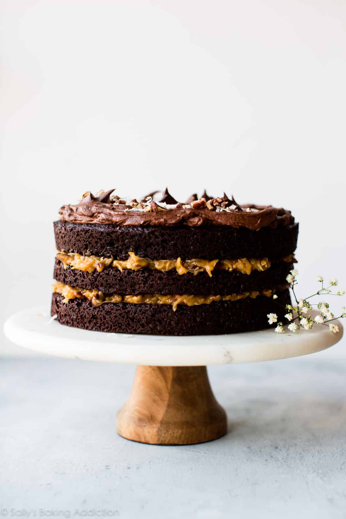 3 layer German chocolate cake on a marble and wood cake stand