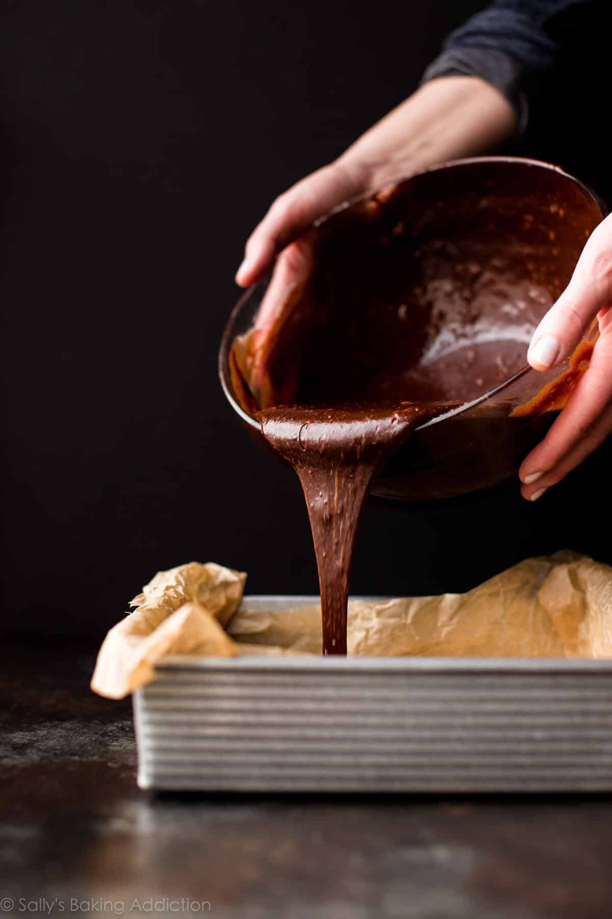 pouring brownie batter into baking pan