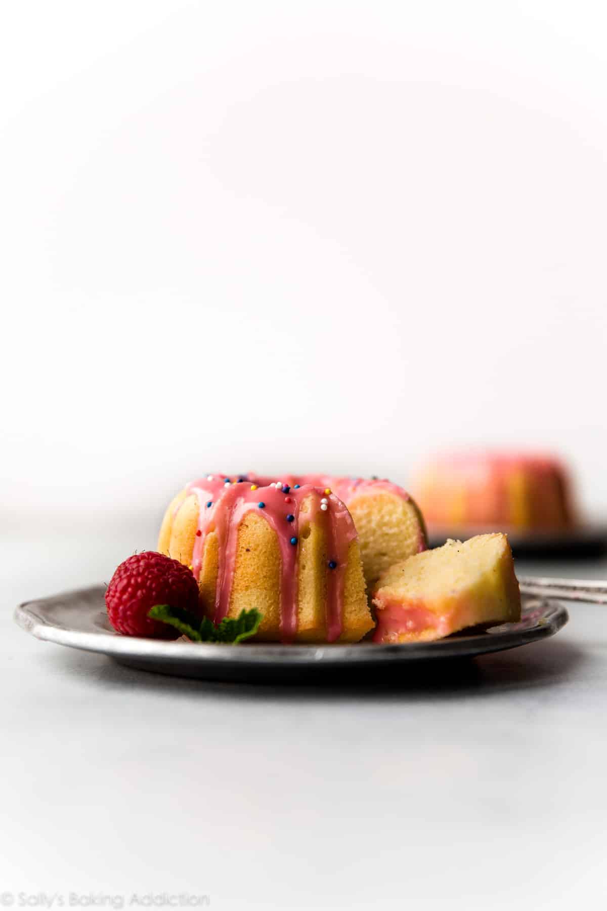 Mini pound cake with raspberry icing and sprinkles on silver plate