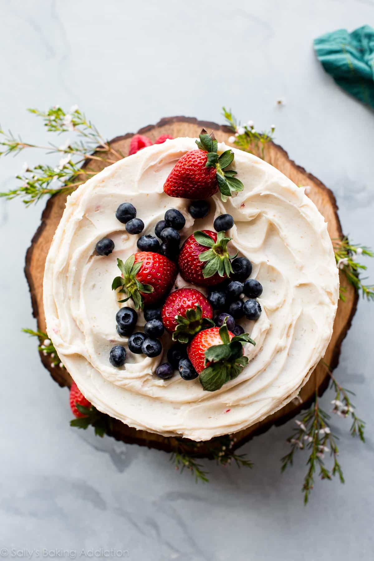 Fresh berries on top of cake on a wood slice cake stand. 