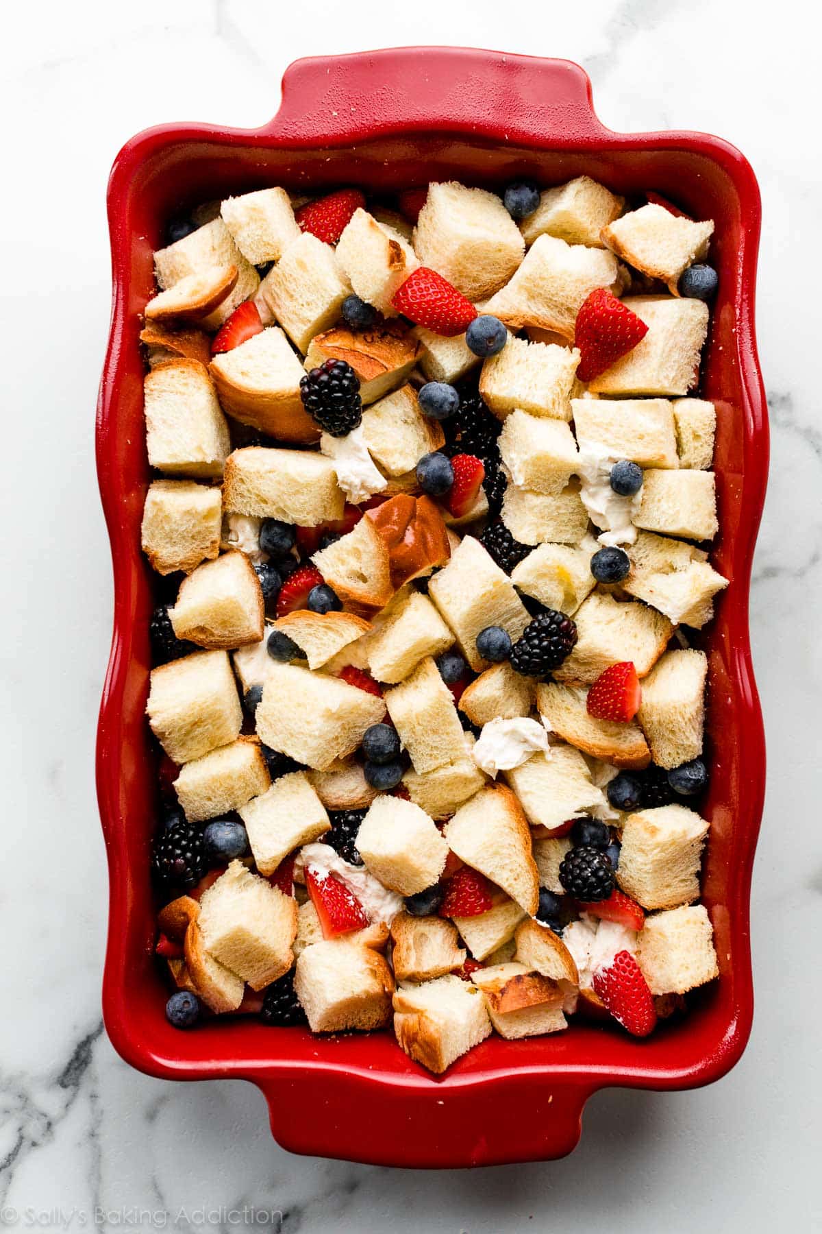 French toast with berries in a red casserole before baking