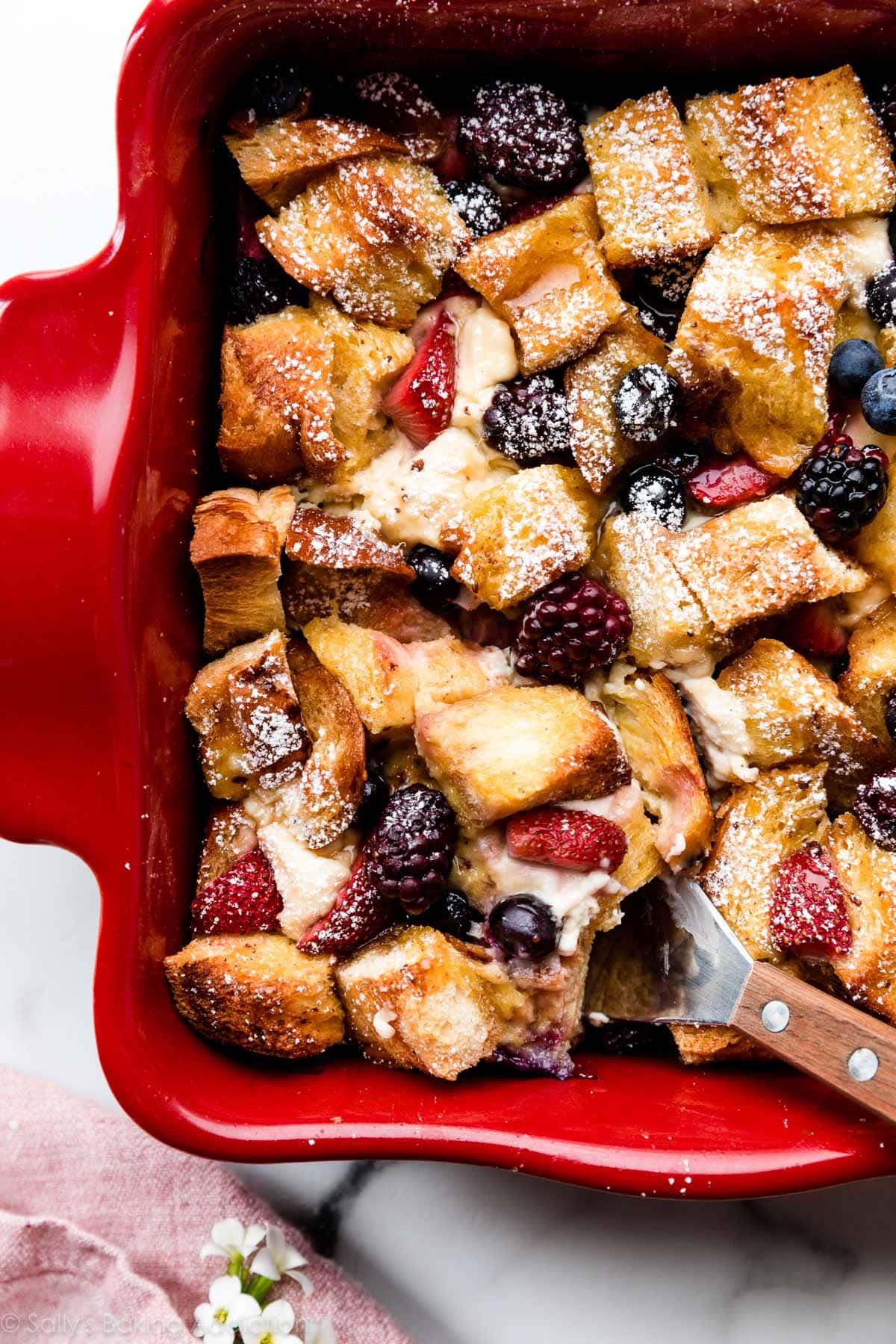 French toast casserole with berries and cream cheese baked on a red plate