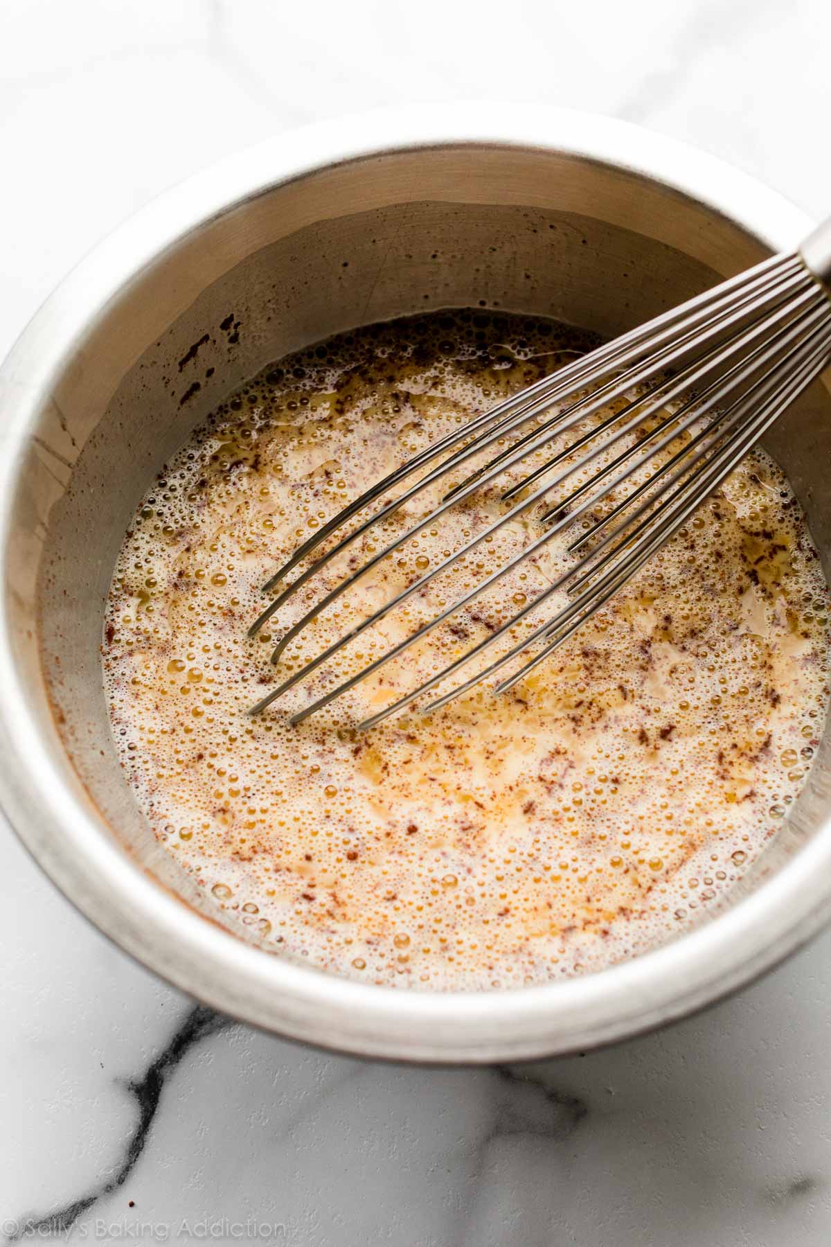 brown sugar cinnamon and egg custard mixture in bowl with whisk