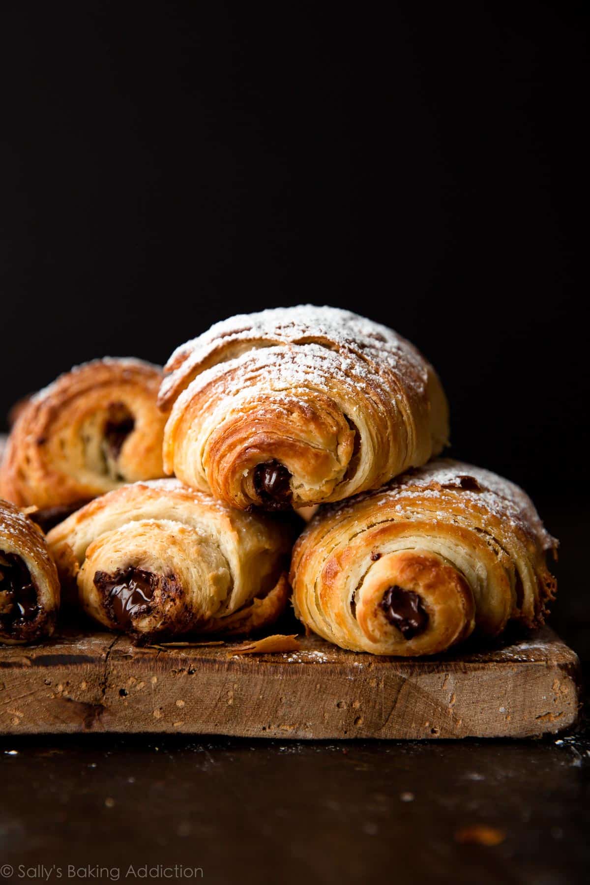 stack of chocolate croissants on a wood serving tray