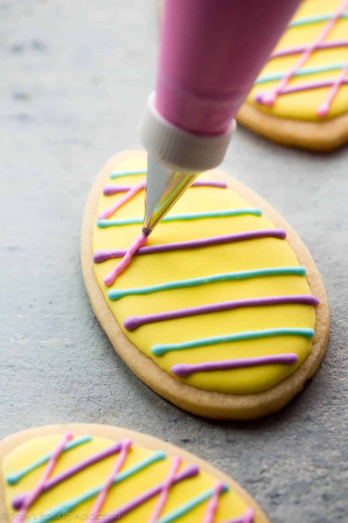 piping details onto an Easter egg sugar cookie