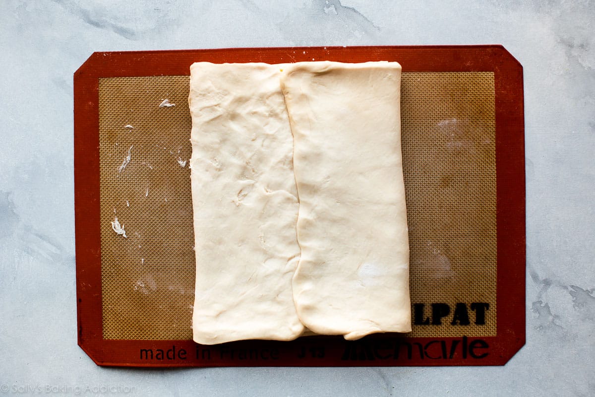 overhead image of folded croissant dough on a silpat baking mat