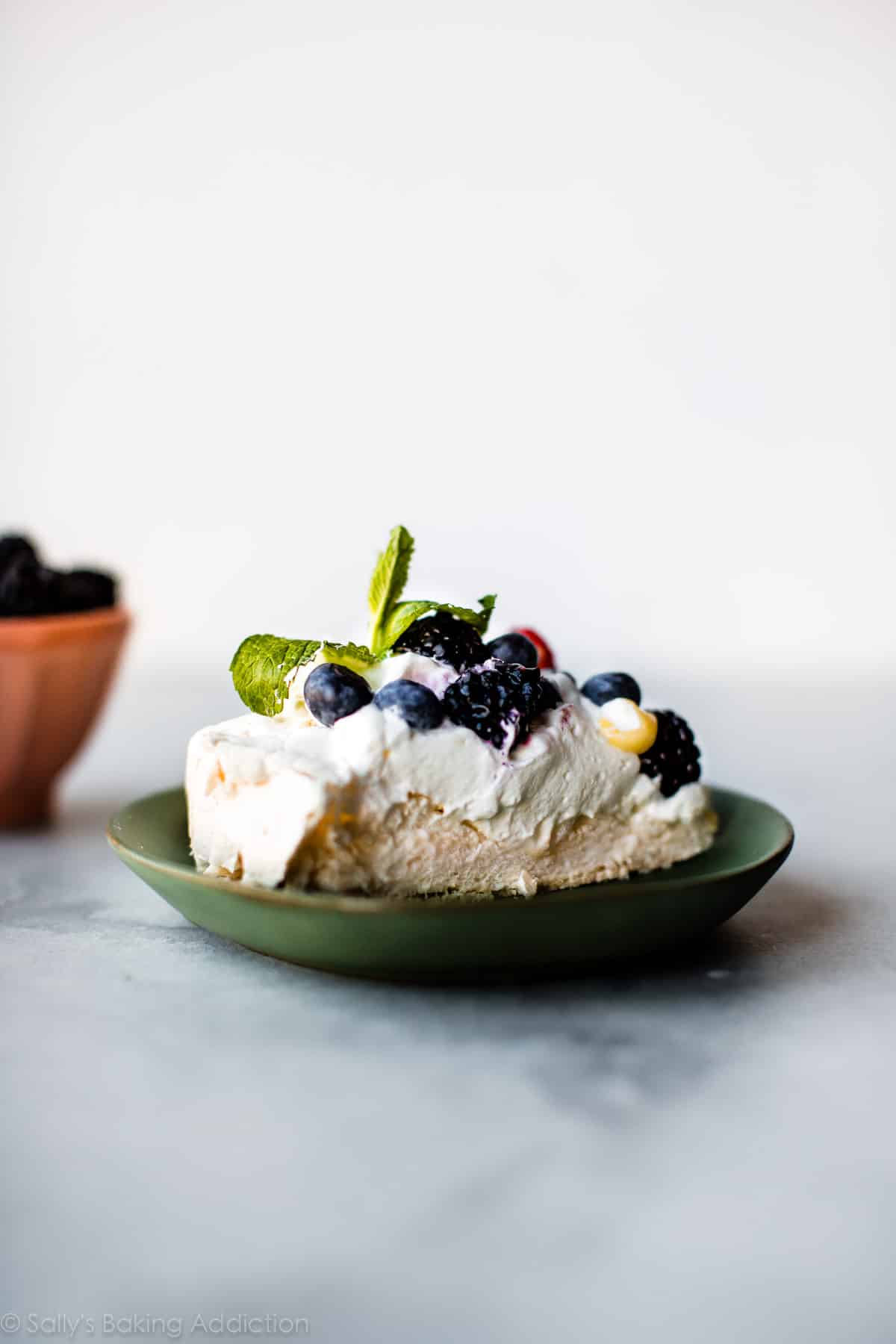 slice of pavlova with fresh fruit topping on a green plate