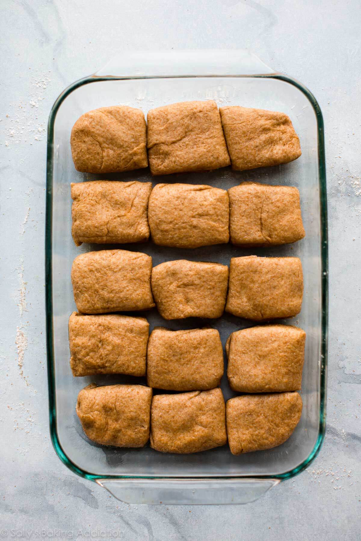 whole wheat dinner rolls in a glass baking dish before baking