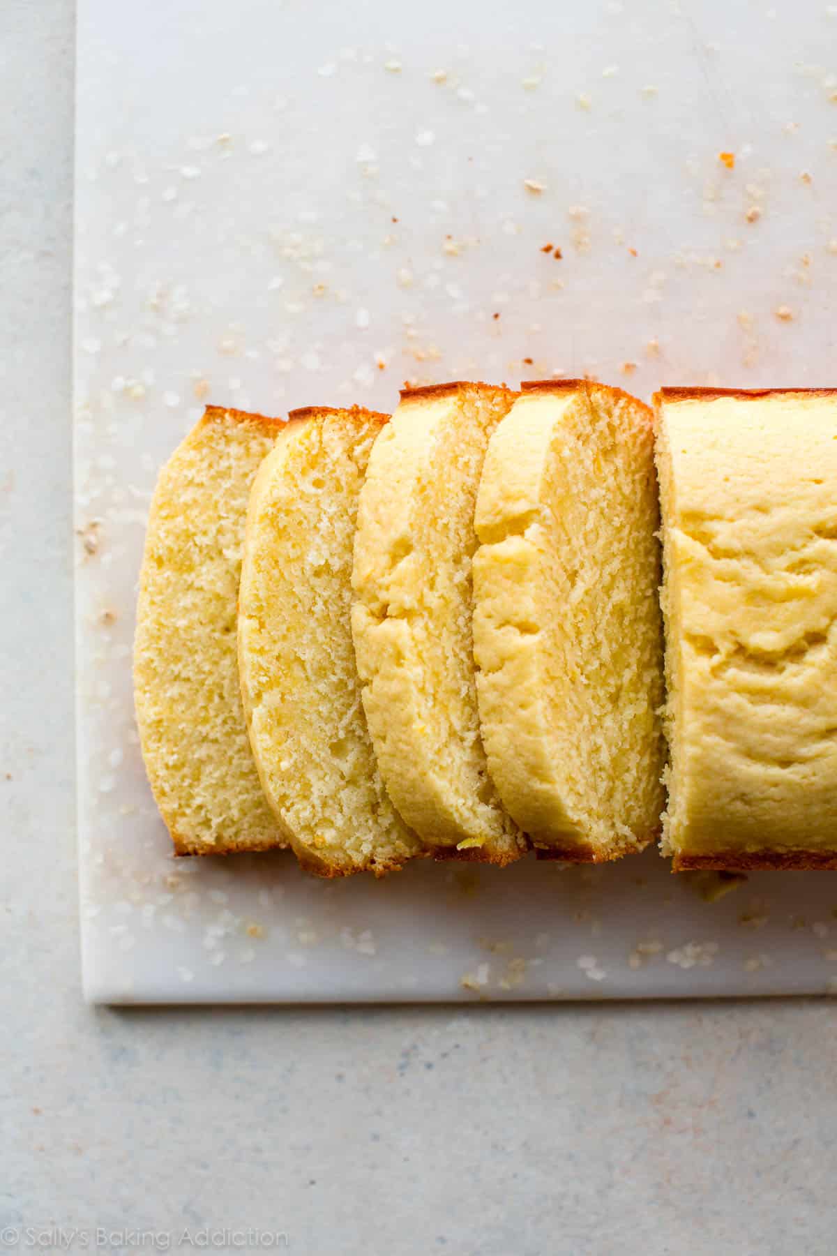 lemon pound cake cut into slices on a white cutting board