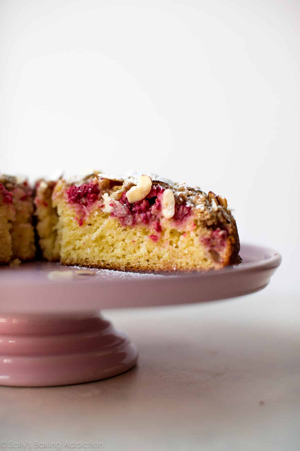 raspberry almond crumb cake on a pink cake stand