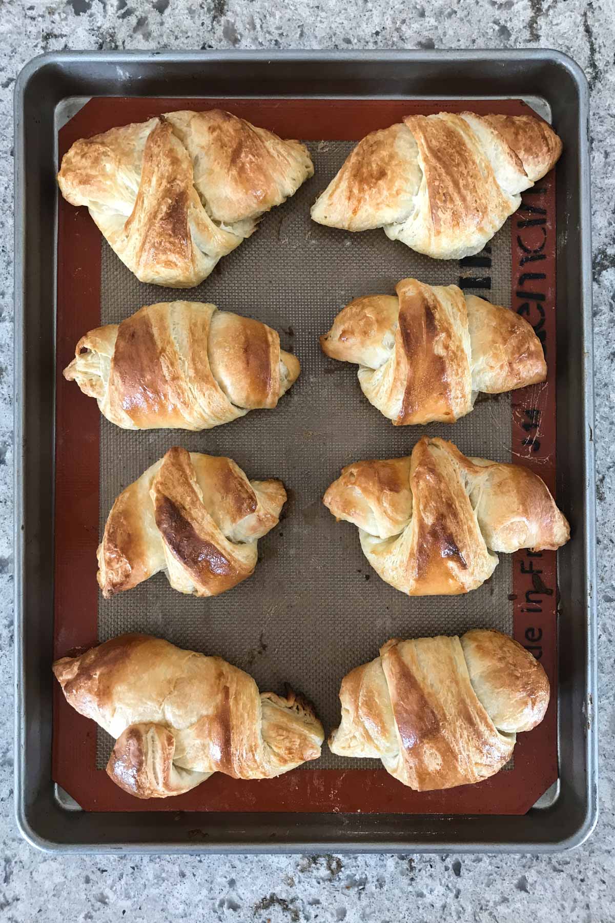 overhead image of croissants on a baking sheet after baking