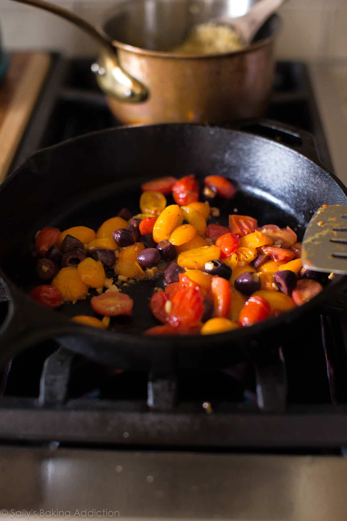 tomato, garlic, and olives in a skillet on the stove