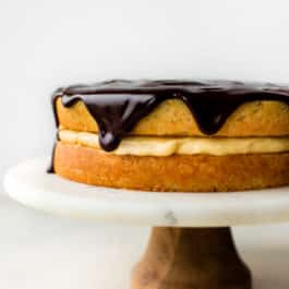 Boston cream pie on a wood and marble cake stand