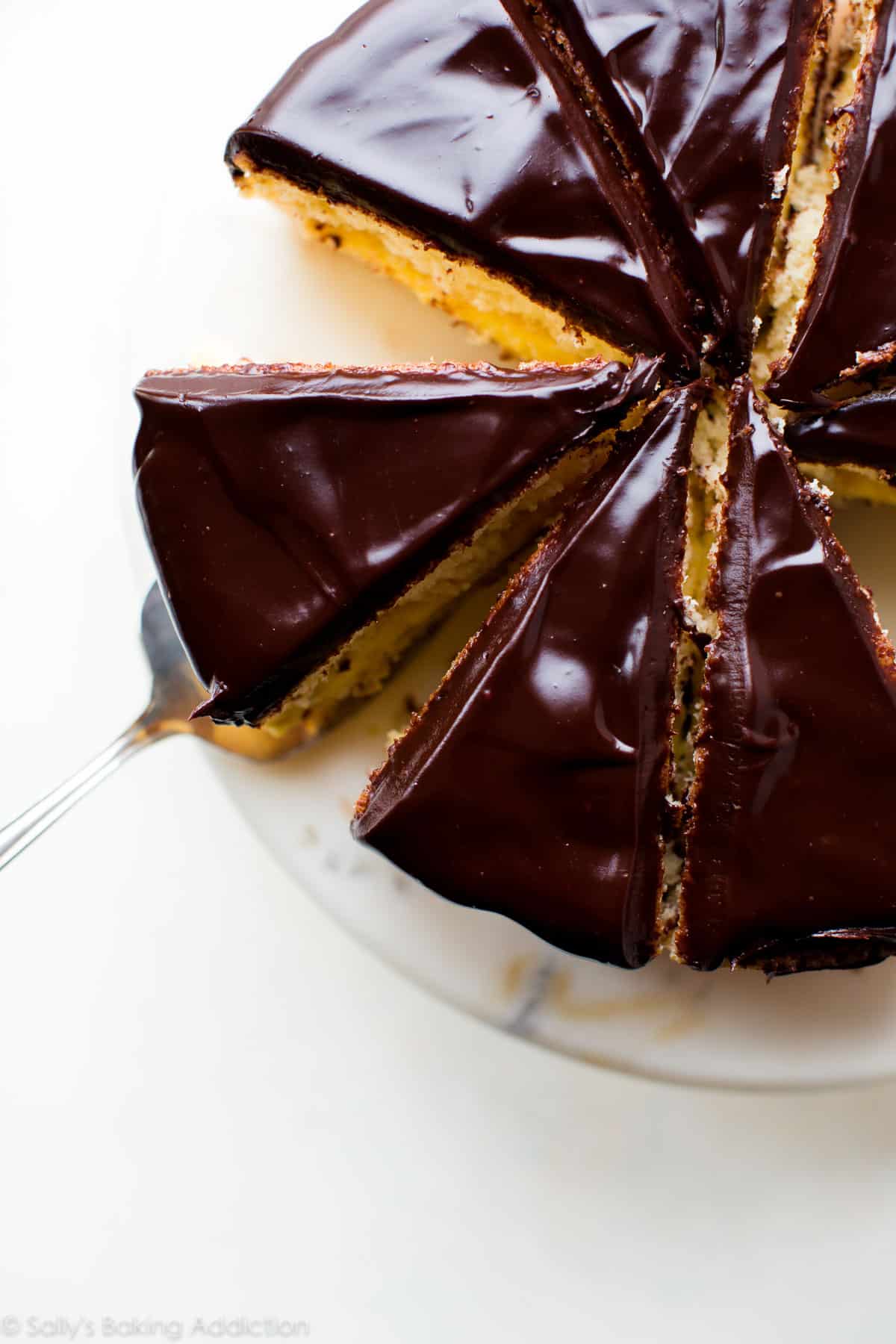 overhead image of Boston cream pie on a marble cake stand cut into slices
