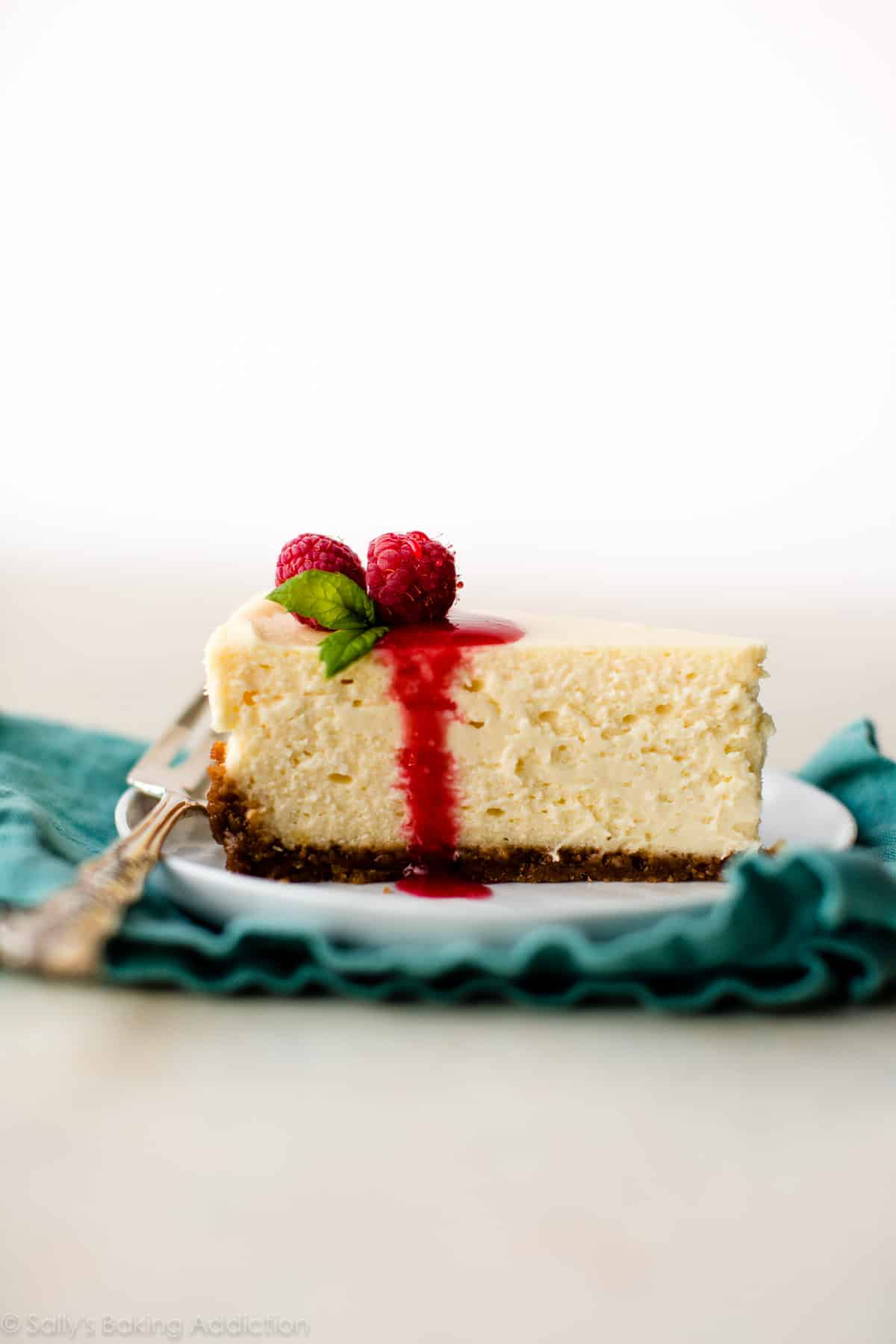 slice of cheesecake on a white plate with raspberry topping