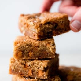 stack of 4 butterscotch blondies with a hand taking the top blondie