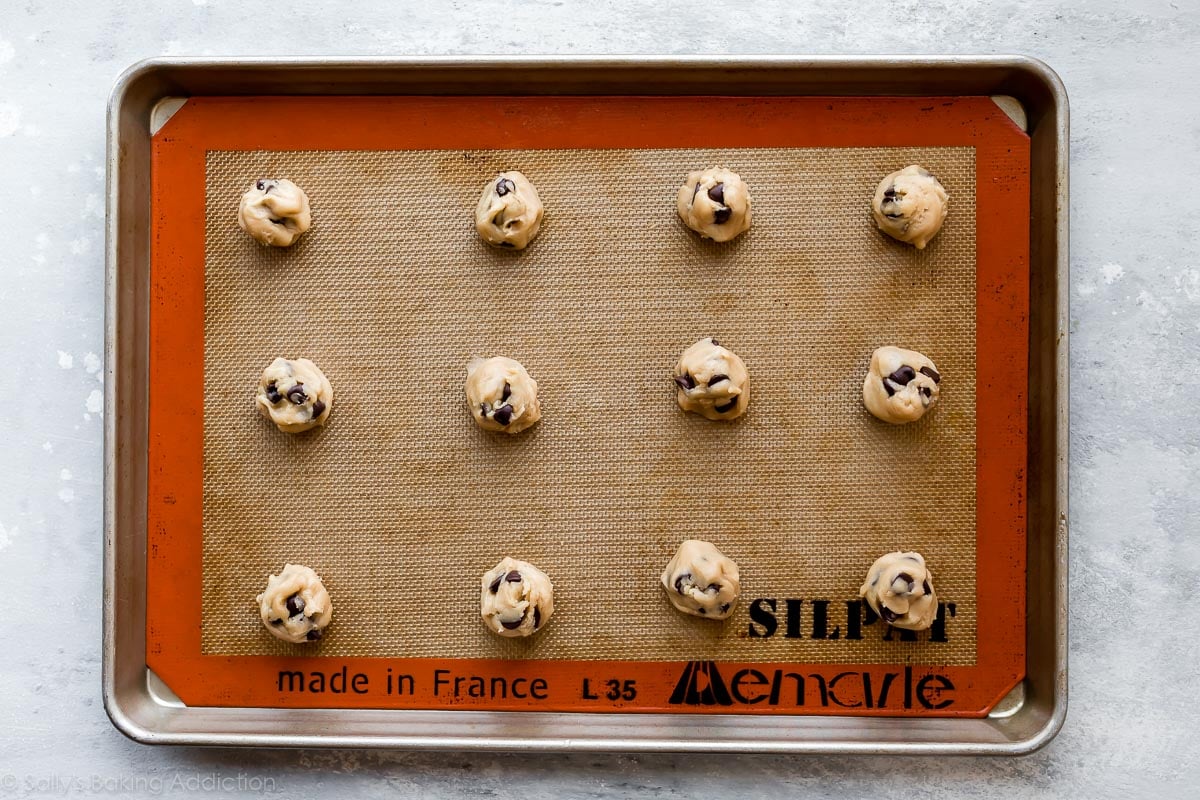 cookie dough balls on a silpat lined baking sheet