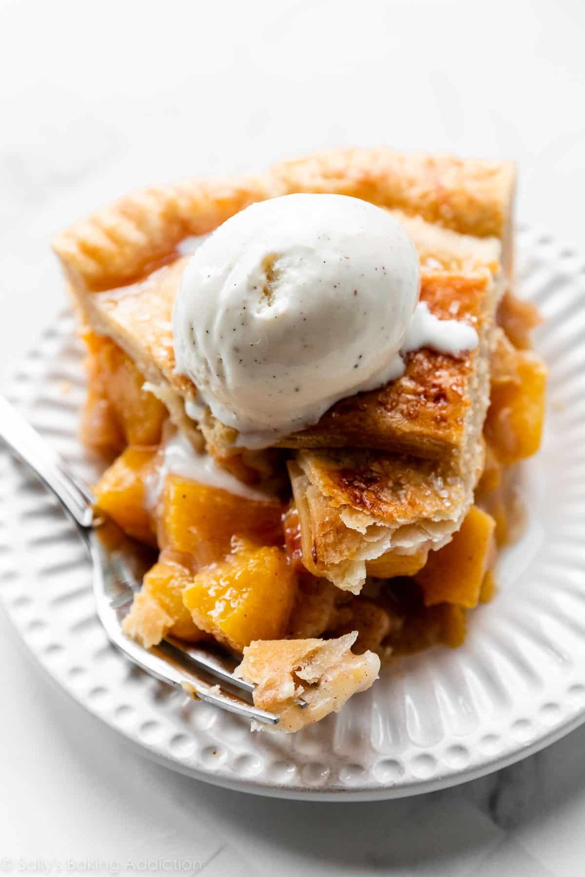 peach pie slice with vanilla ice cream on top.