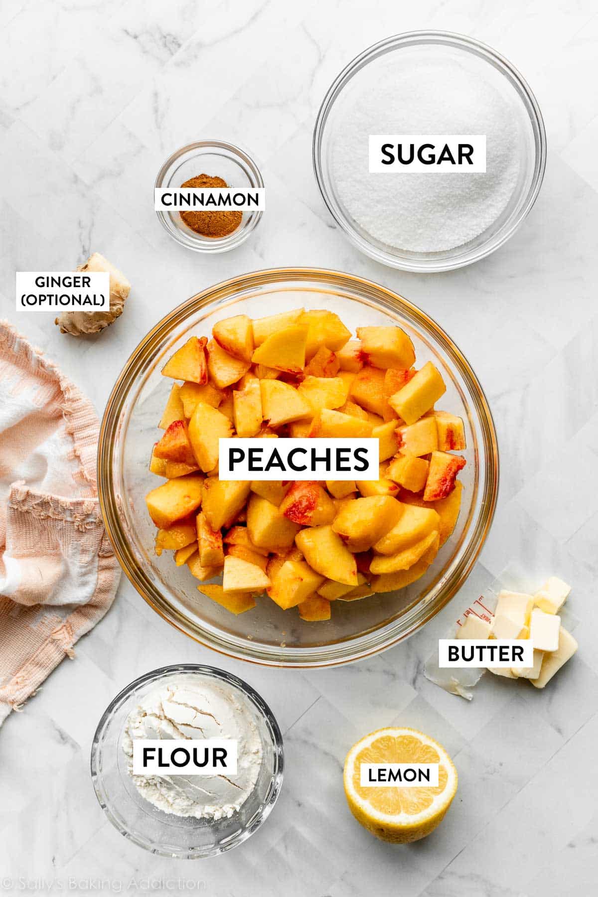 peaches, sugar, butter, lemon, flour, fresh ginger, and cinnamon on counter.