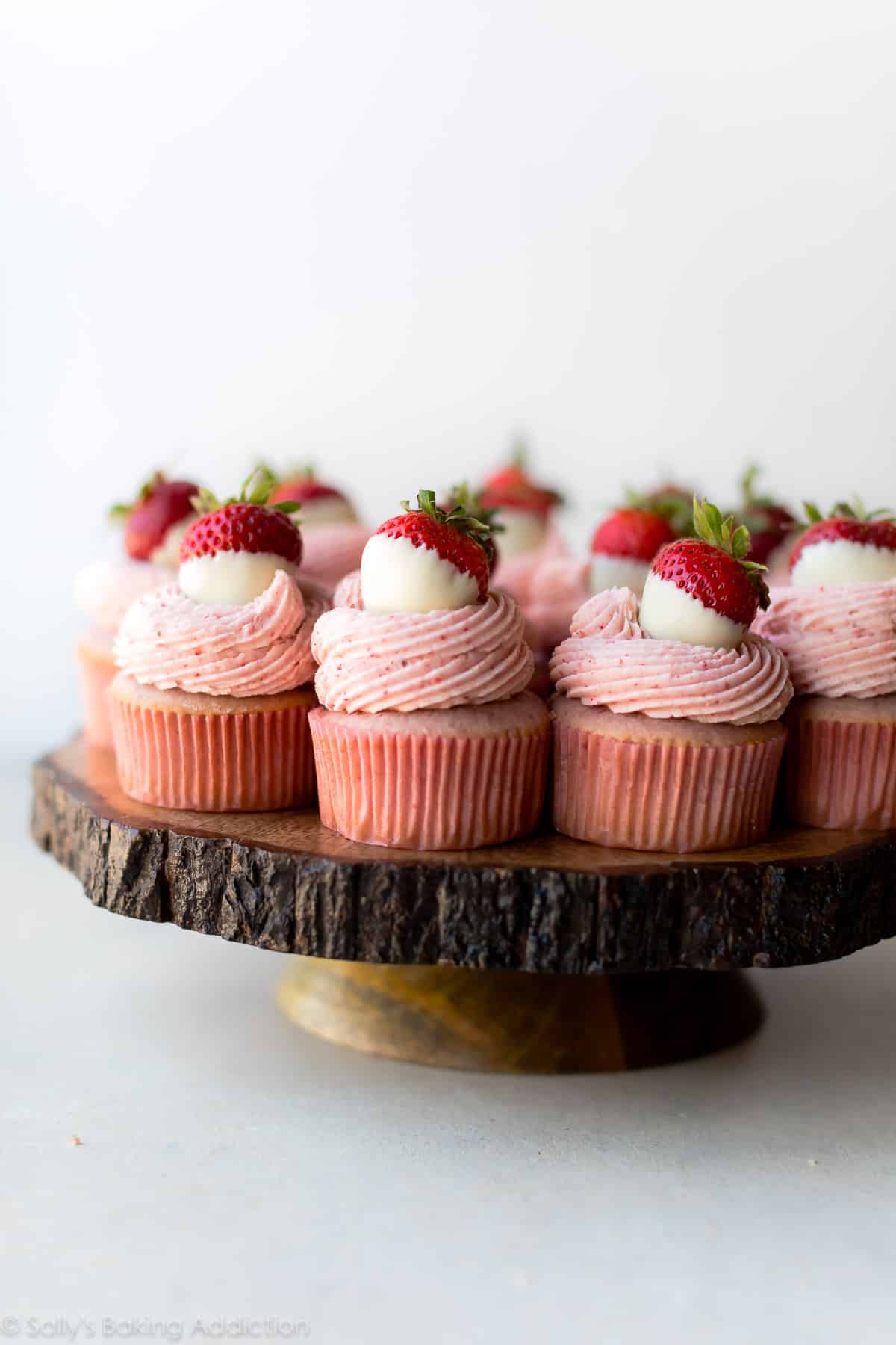 strawberry cupcakes on a wood slice cake stand