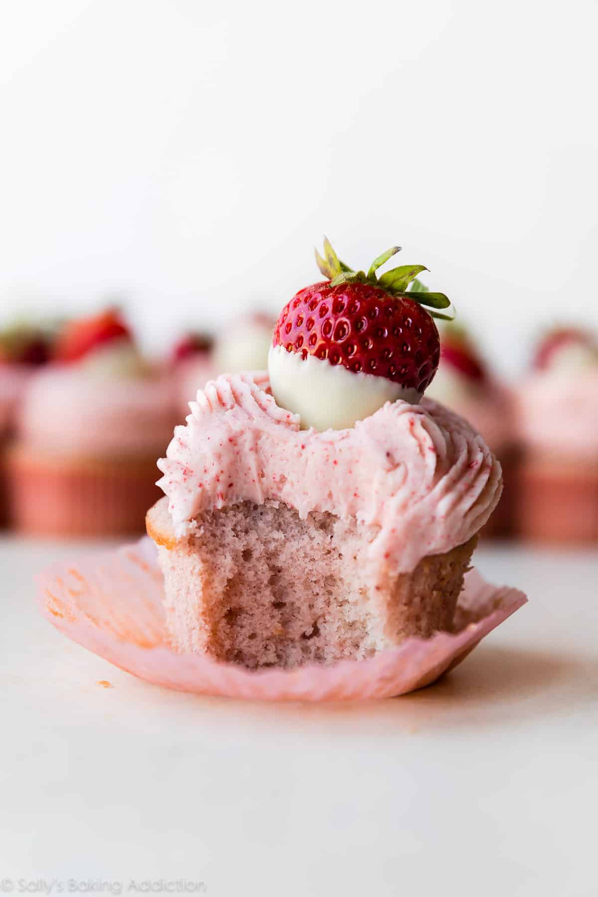 strawberry cupcake with white chocolate frosting and a white chocolate dipped strawberry