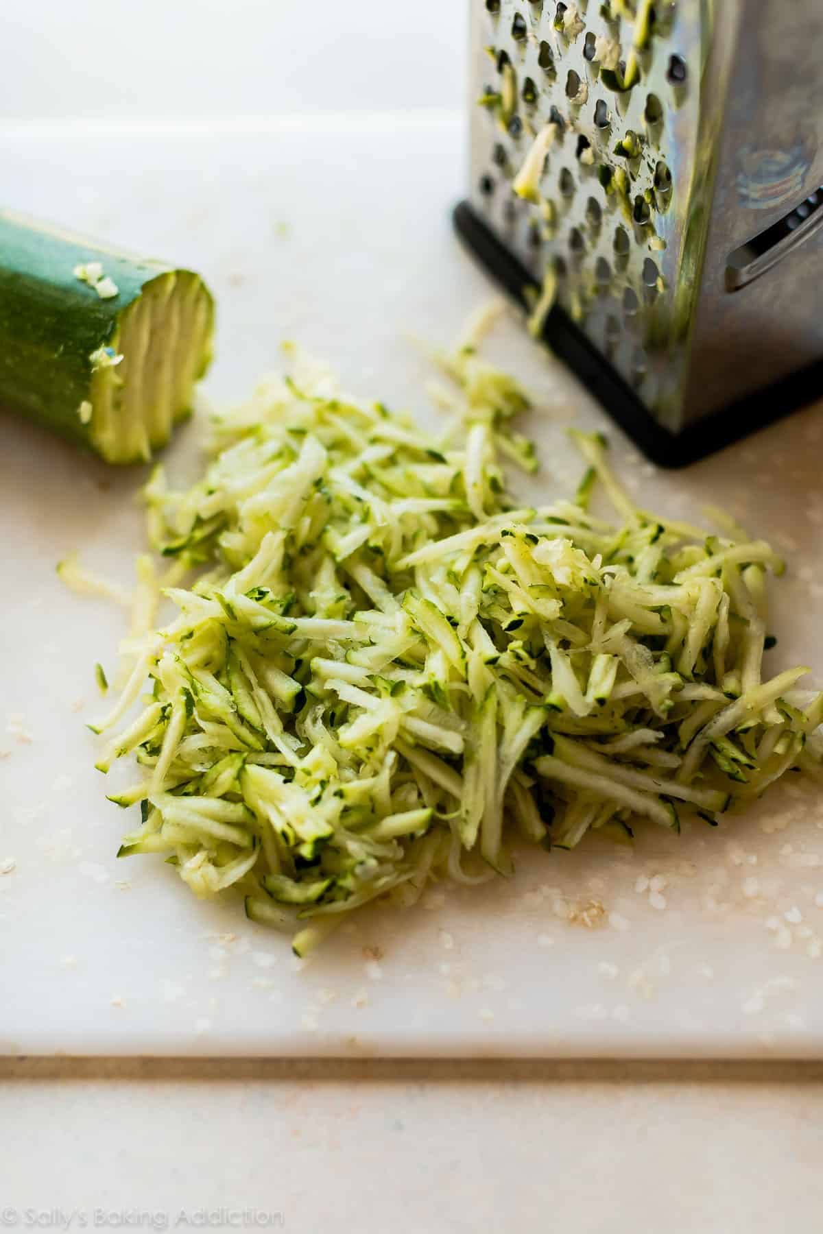 Shredded zucchini on a white cutting board