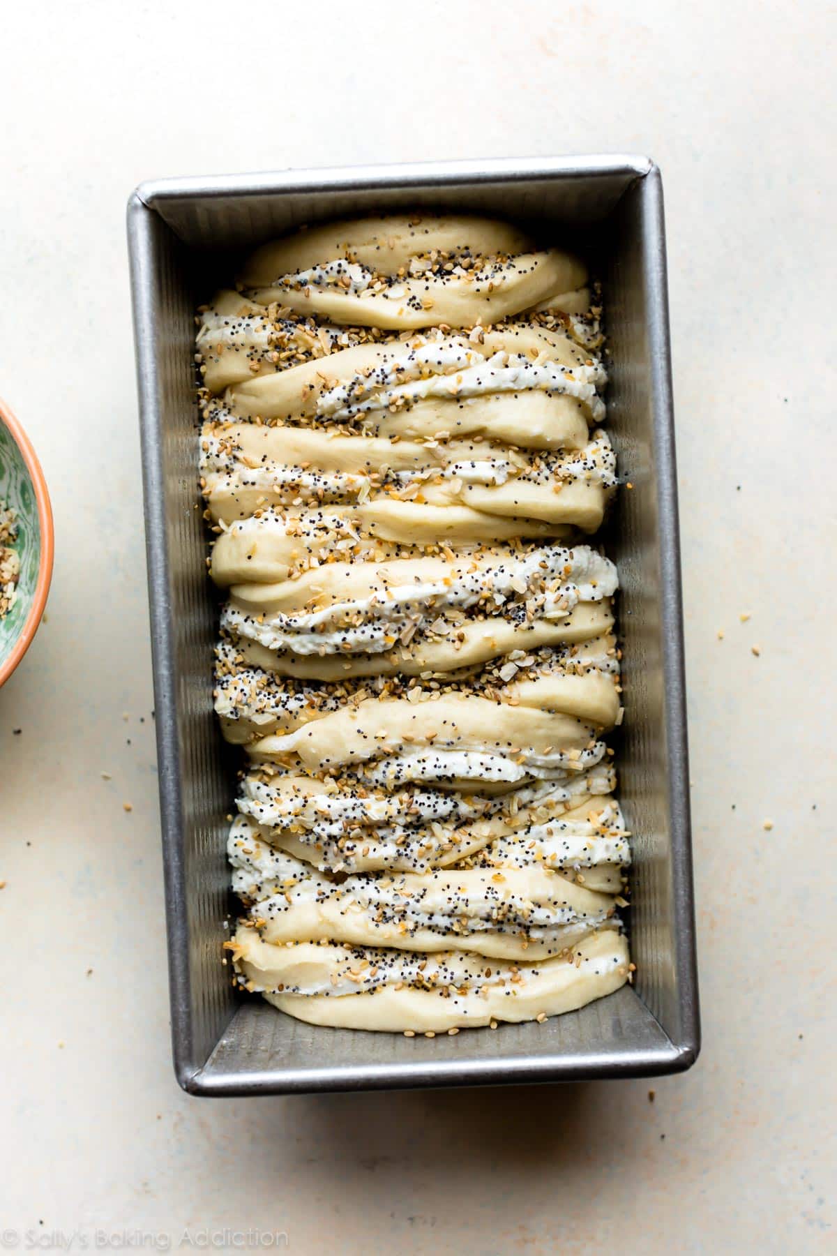 pull apart bread with everything bagel seasoning on top assembled in loaf pan before baking