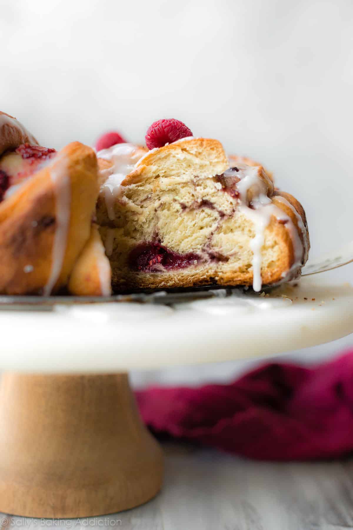 side image of raspberry danish twist bread on marble cake stand on a dessert server