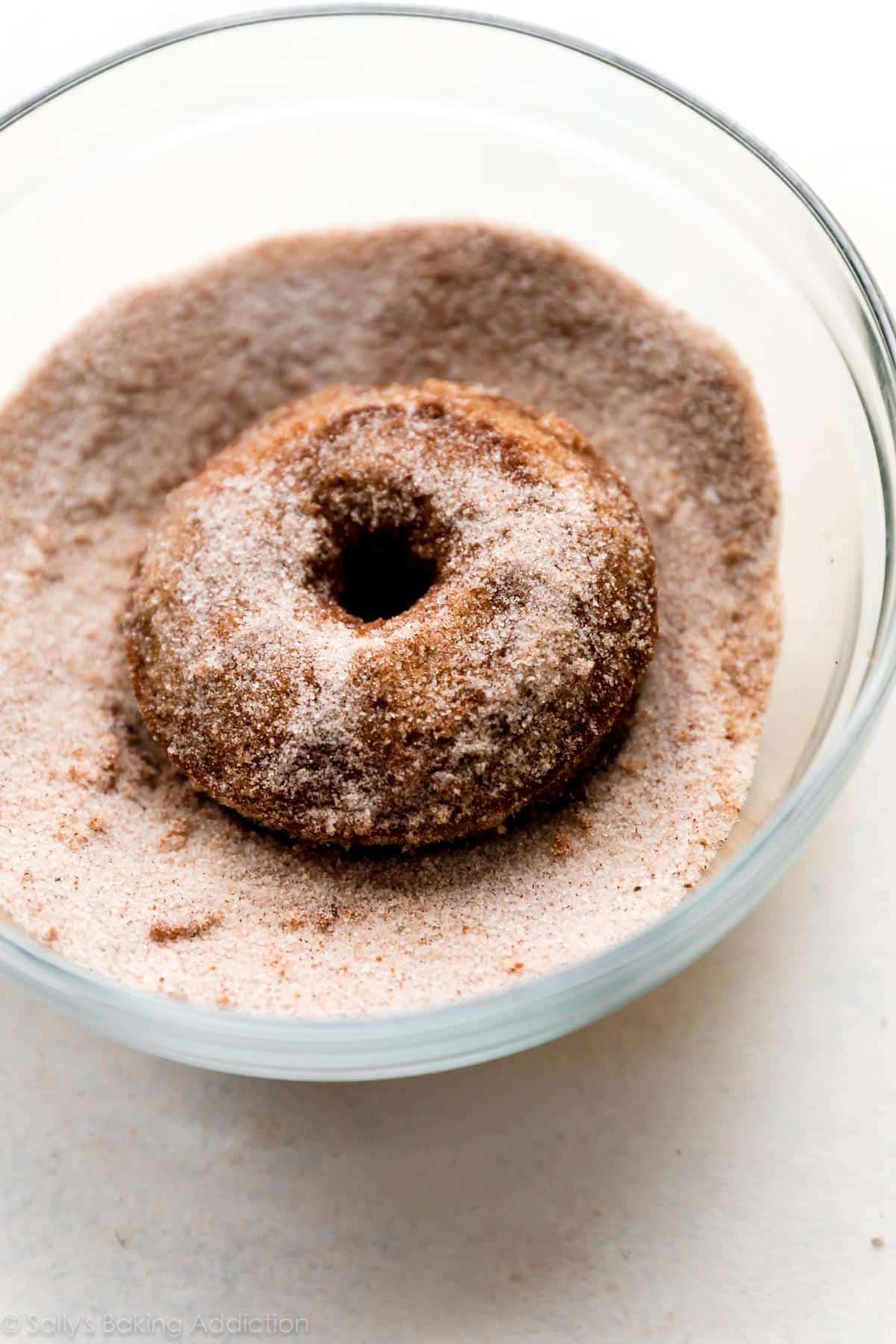 a donut in a glass bowl of apple cider donut topping