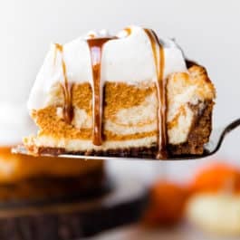 slice of pumpkin swirl cheesecake on a dessert server with salted caramel