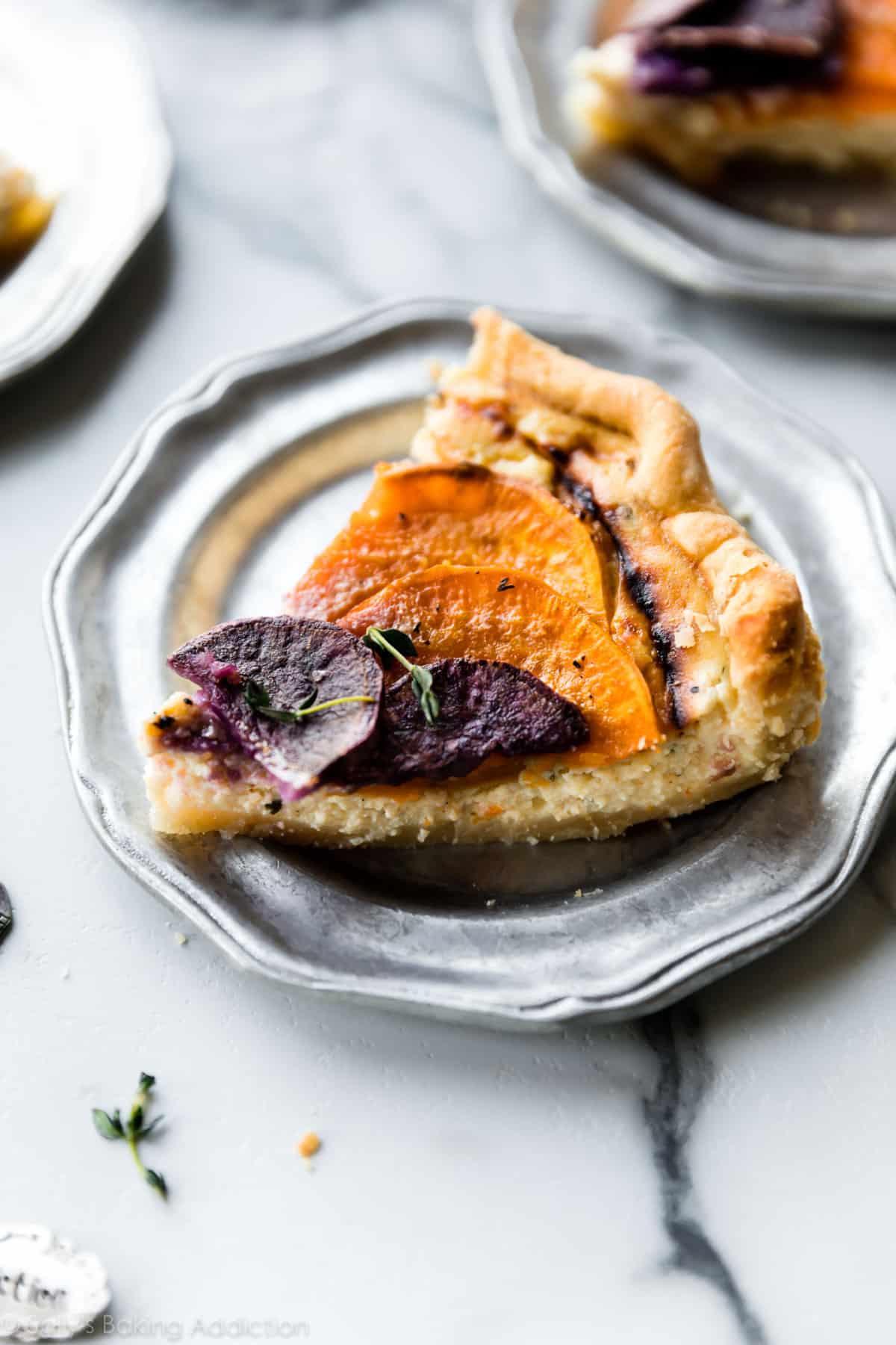 Slice of savory vegetable tart on a silver plate