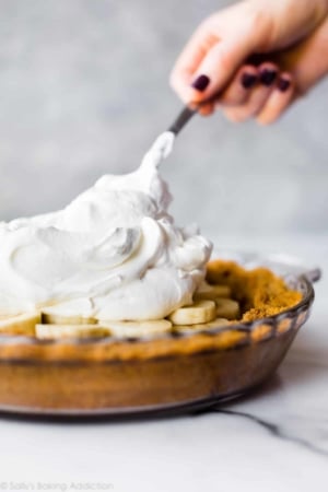 spreading fluffy homemade whipped cream on banoffee pie
