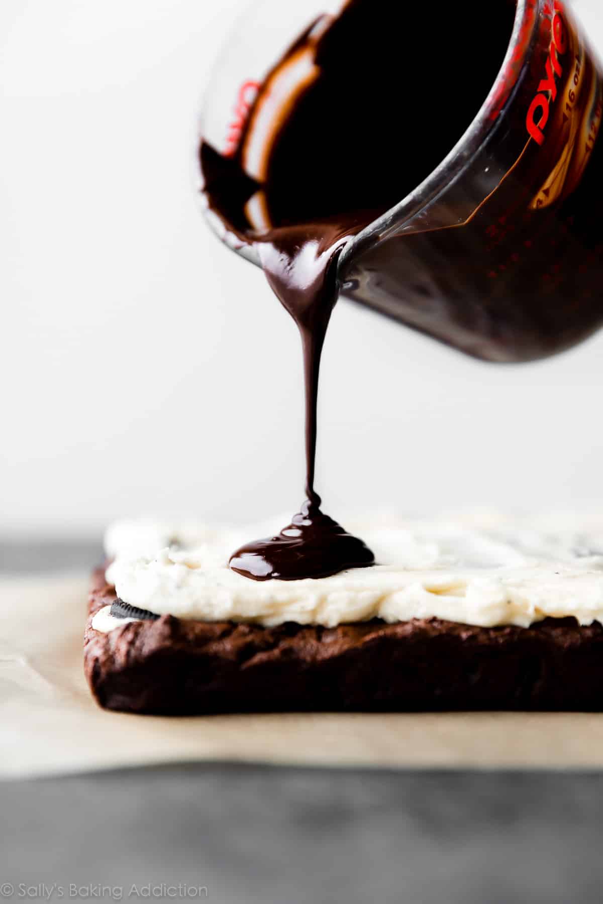 Pouring chocolate topping on brownies