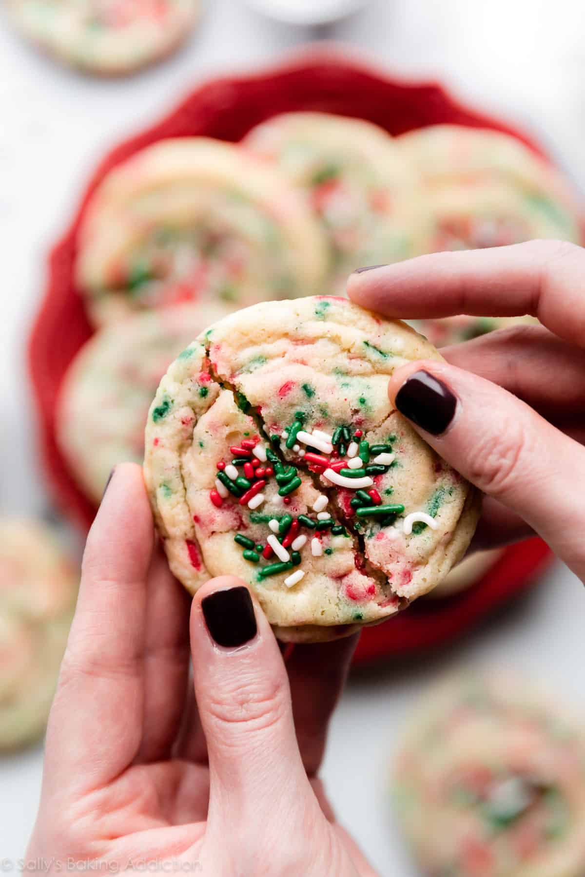 hands breaking Christmas sugar cookie in half