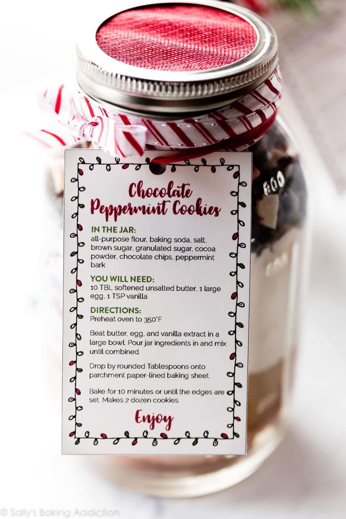 glass jar with ingredients for cookies decorated with ribbon and a recipe card