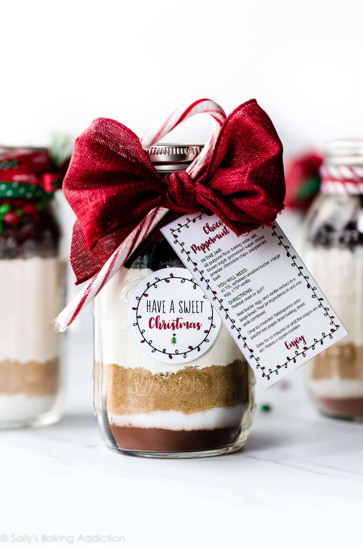 glass jar with ingredients for cookies decorated with ribbon and a recipe card