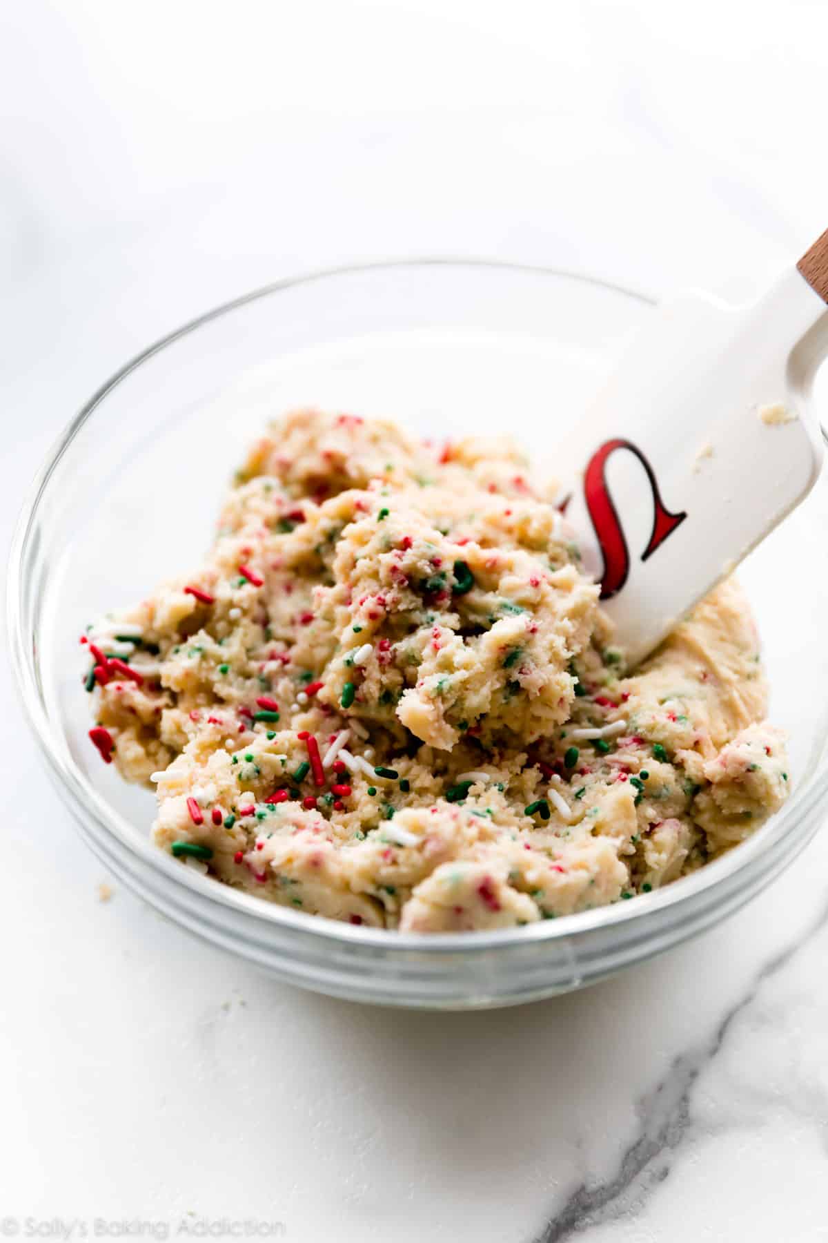Christmas sugar cookie dough with red and green sprinkles in a glass bowl