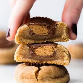 stack of peanut butter cup cookies with a hand grabbing the top cookie