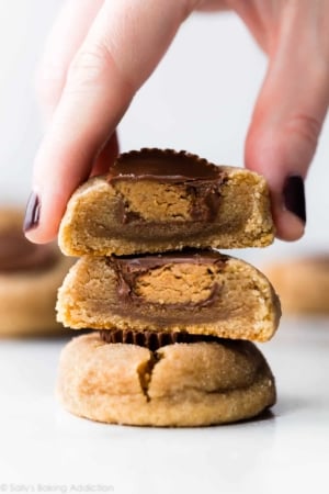 stack of peanut butter cup cookies with a hand grabbing the top cookie