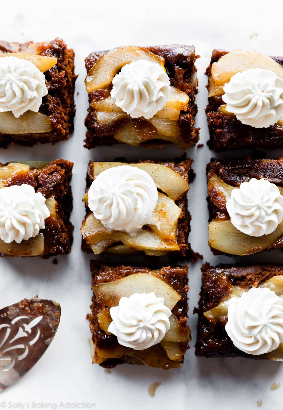 Squares of upside down pear gingerbread topped with whipped cream