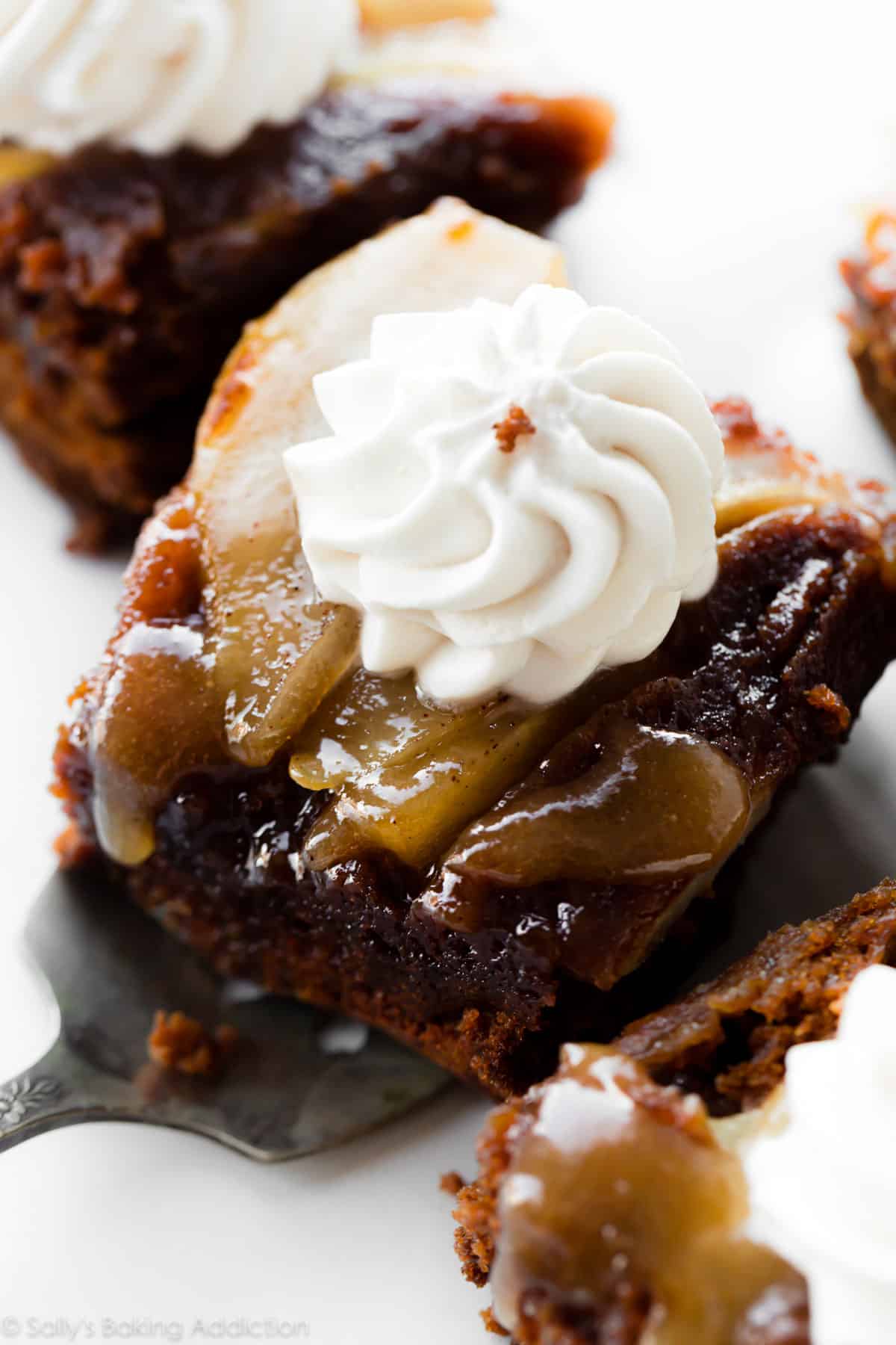 Slice of upside-down pear gingerbread cake topped with whipped cream