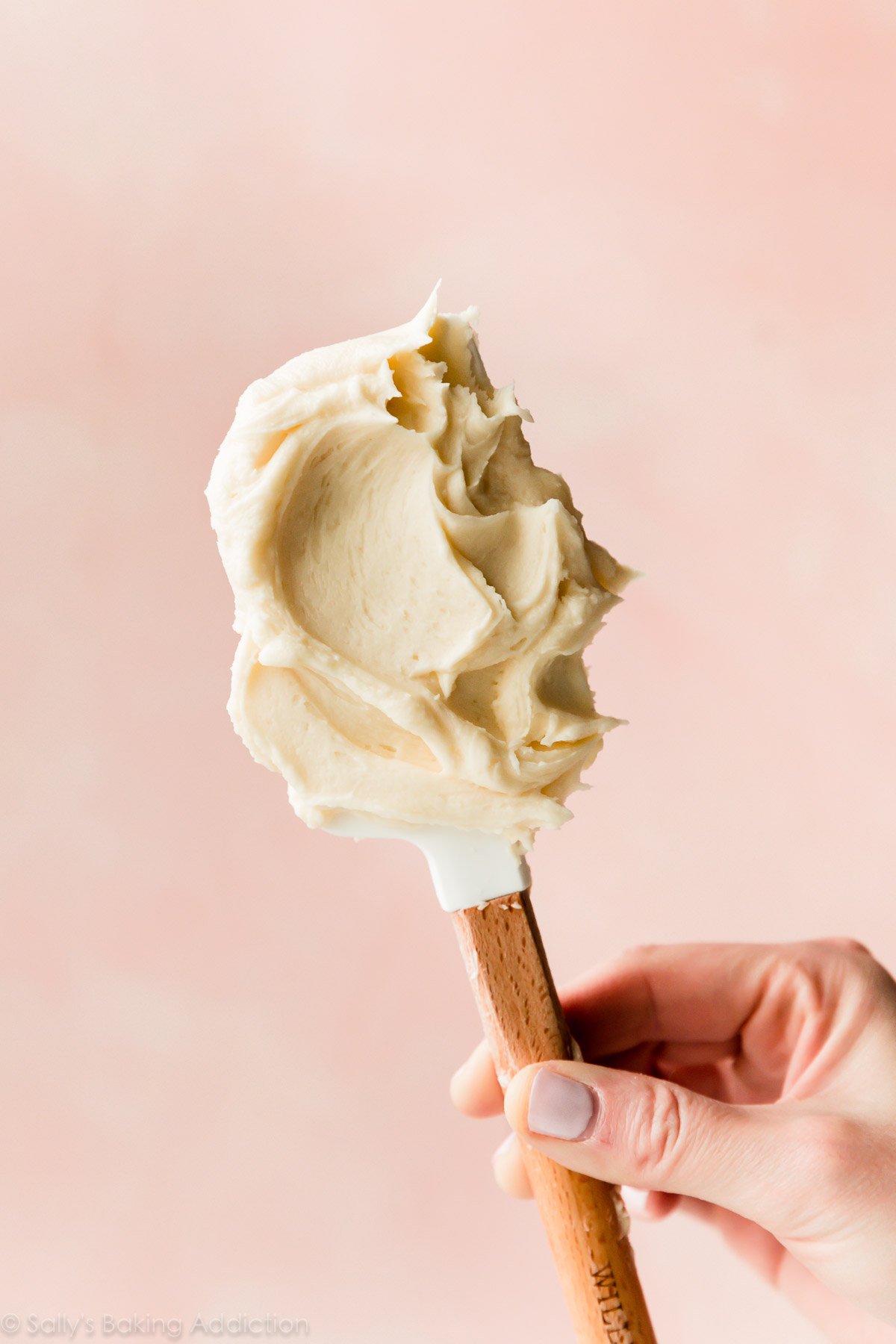 hand holding a spatula with champagne frosting