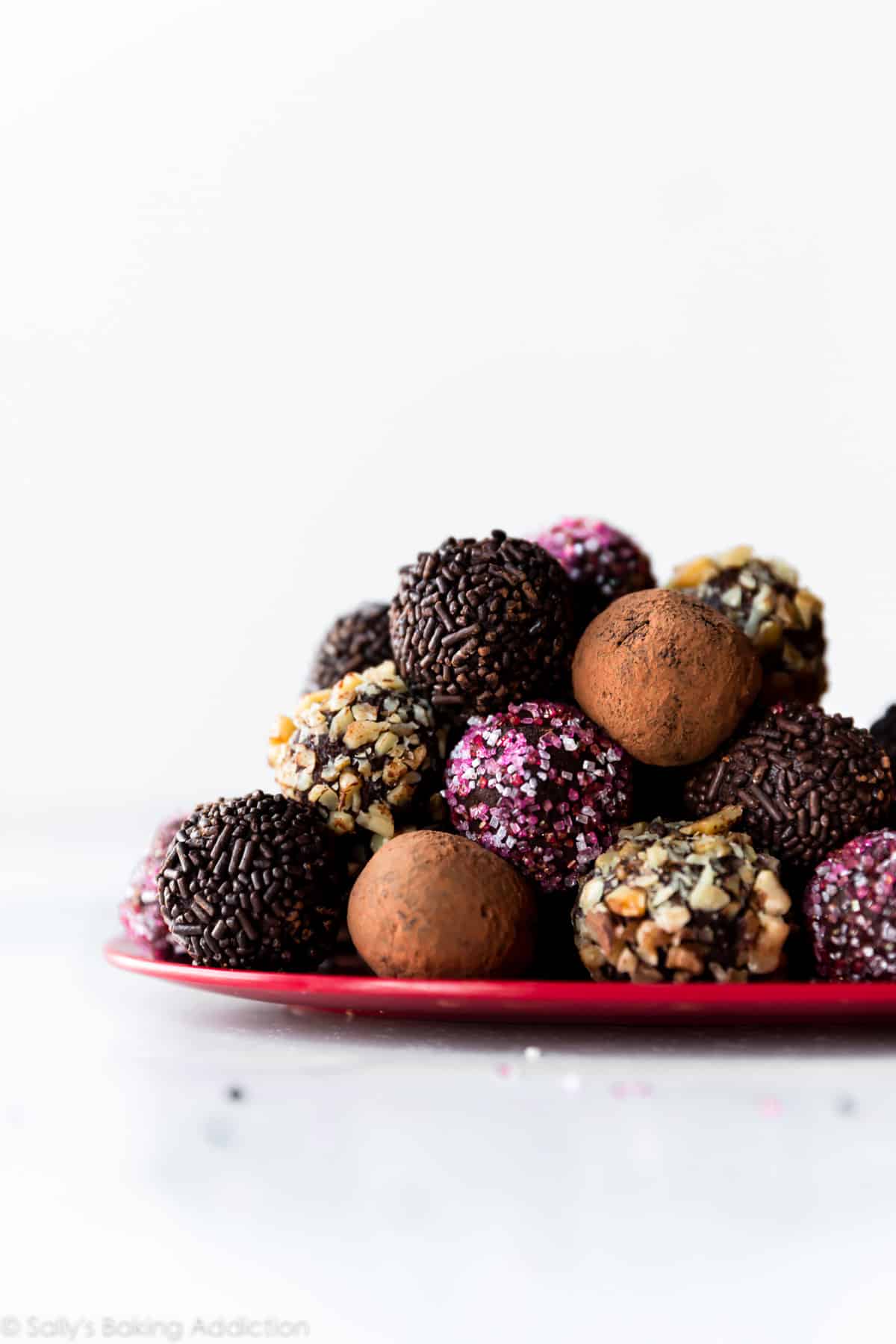 stack of chocolate truffles rolled into cocoa powder and sprinkles on a red plate