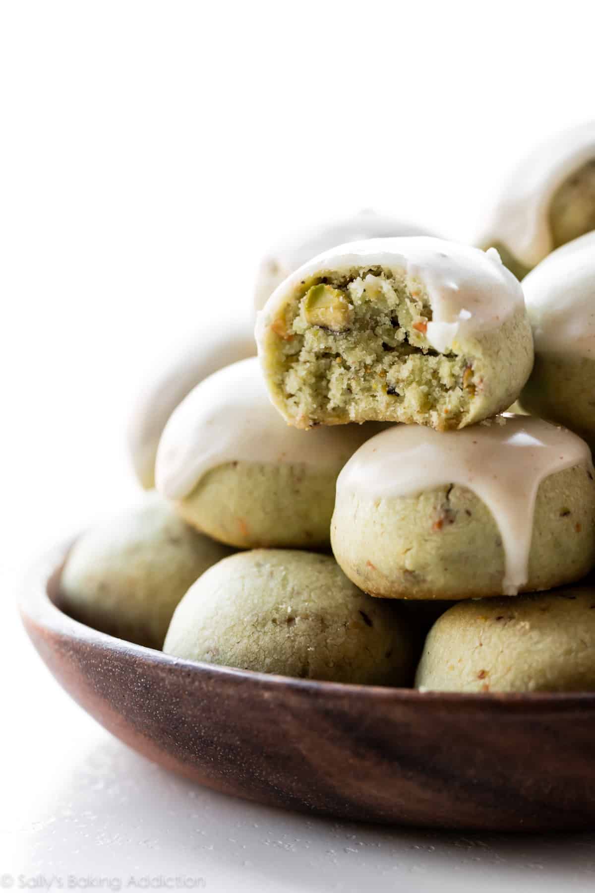 Pistachio cookies with brown butter icing on a wood plate