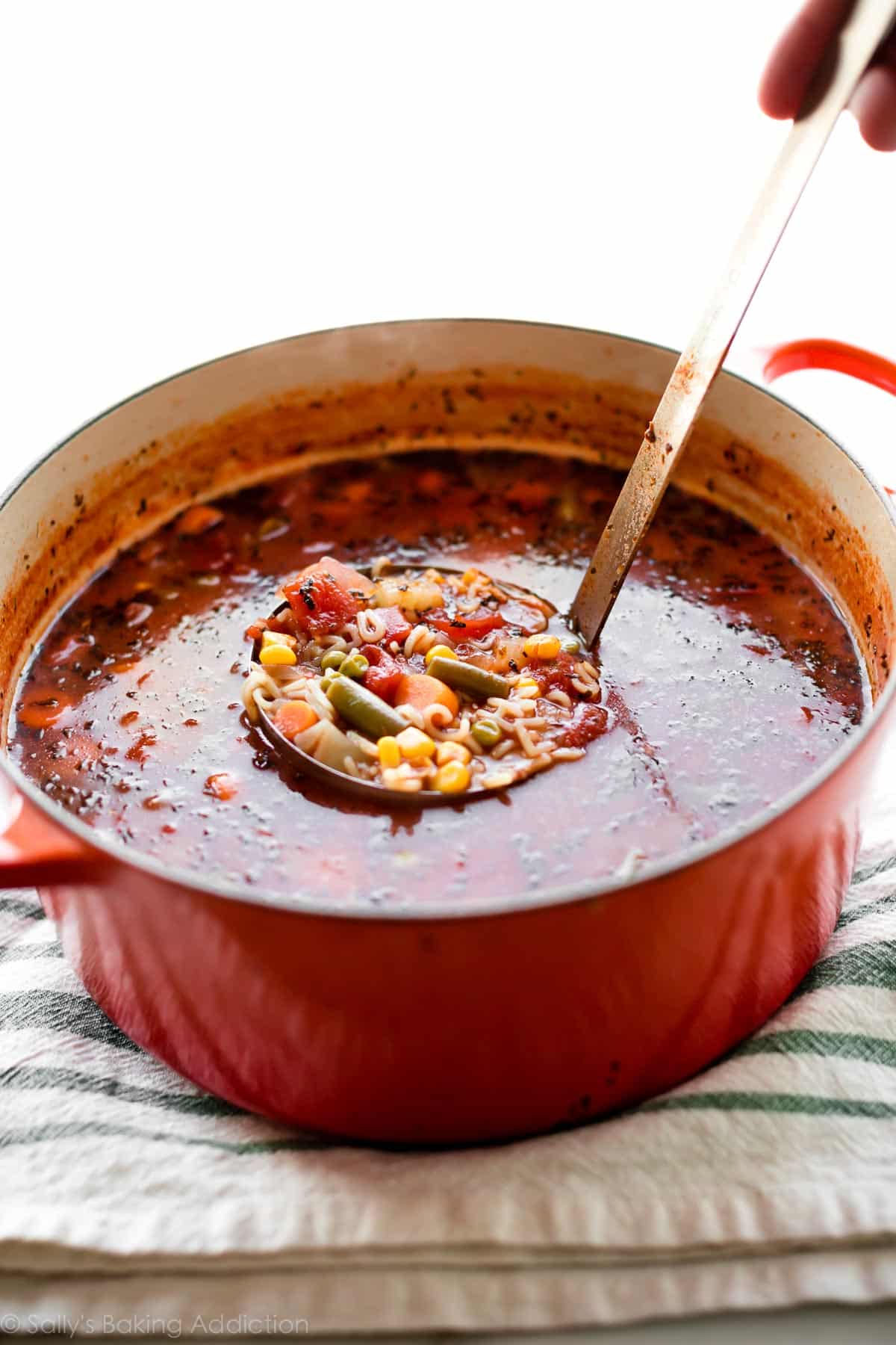 alphabet vegetable soup in a red pot with a ladle