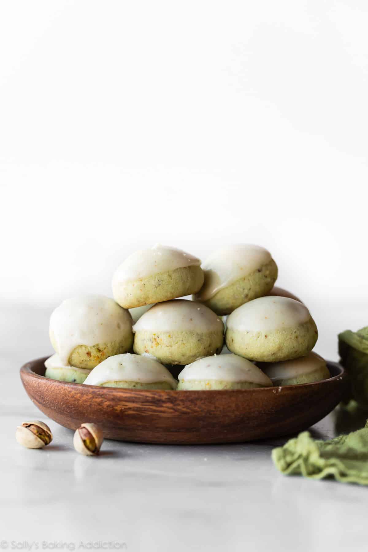 Pistachio drop cookies with brown butter icing on a wood plate