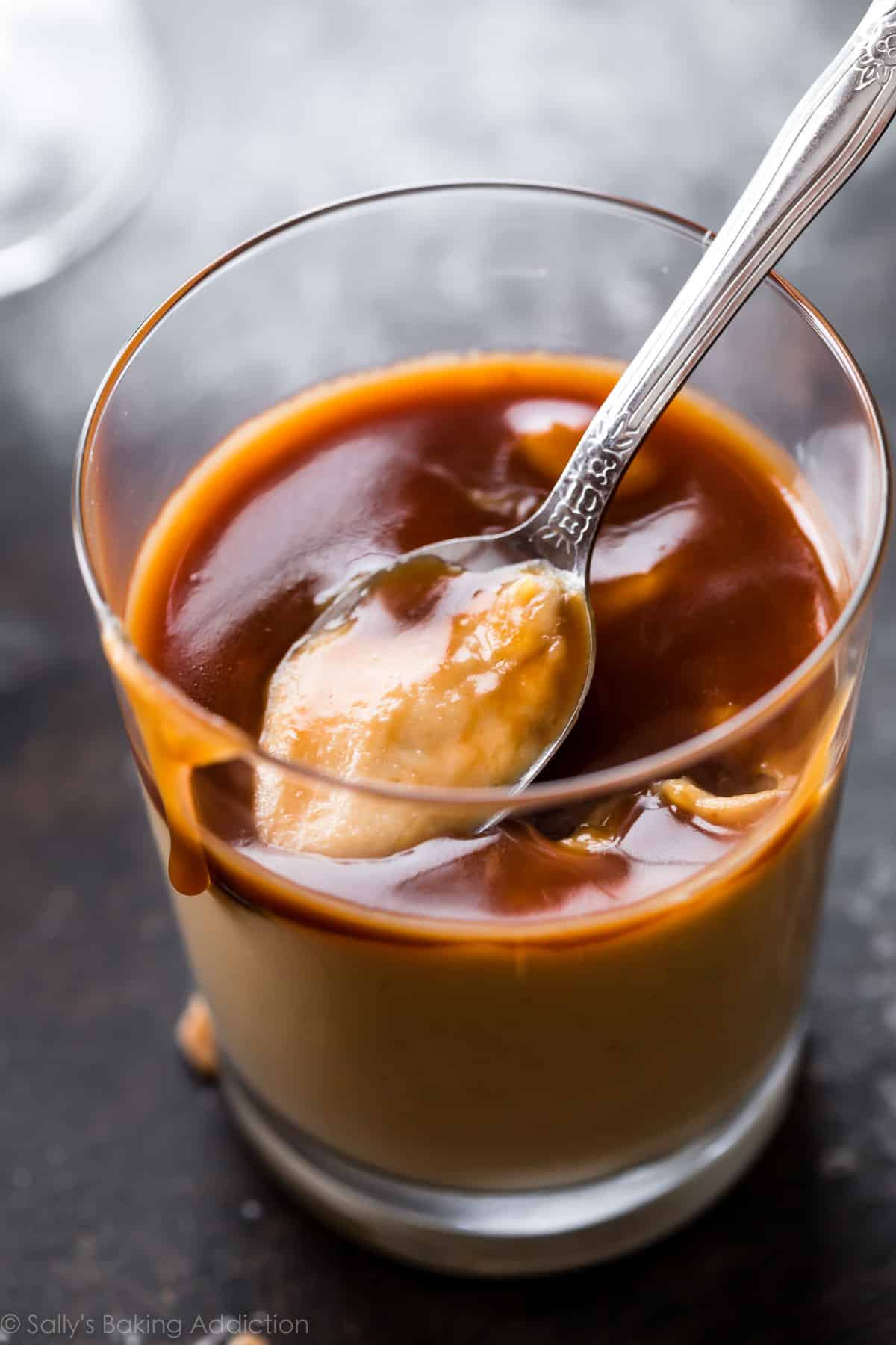 Spoonful of homemade butterscotch pudding with salted caramel in glass cup