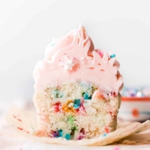 Sprinkle cupcake cut in half showing sprinkles with pink frosting